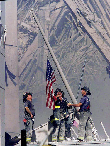 Firefighters raise a flag at the World Trade Center in New York on Tuesday, Sept. 11, 2001, as work at the site continues after hijackers crashed two airliners into the center. (AP Photo/The Record, Thomas E. Franklin)